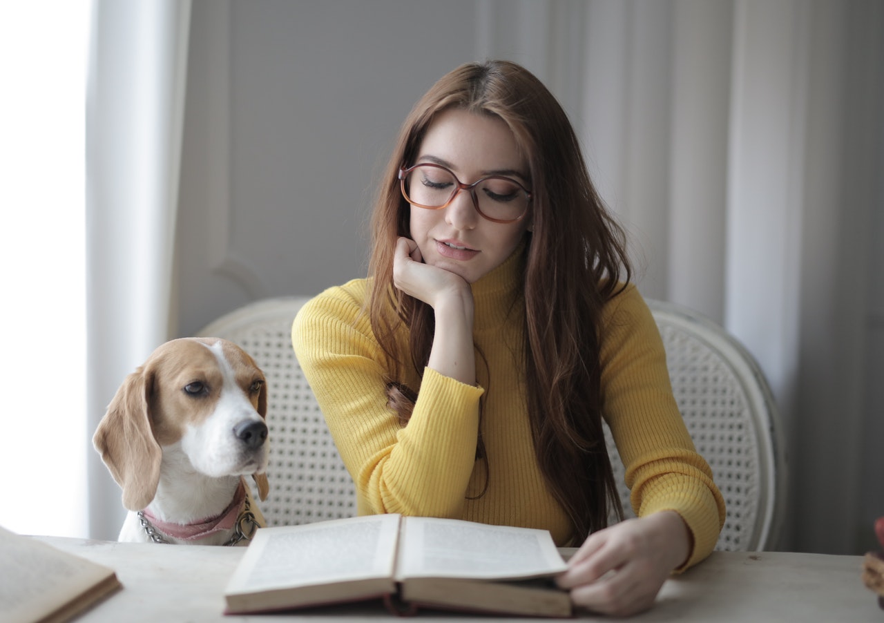 Žena čte dokumenty - rodokmen psa a rodný list, vedle ní pes.